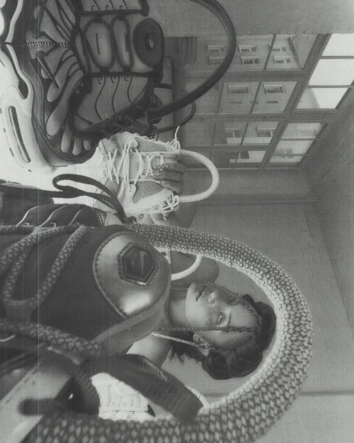 Monochrome studio shot of a woman with a soccer ball, sneakers, and athletic gear, creating an upside-down, surreal composition with natural light.