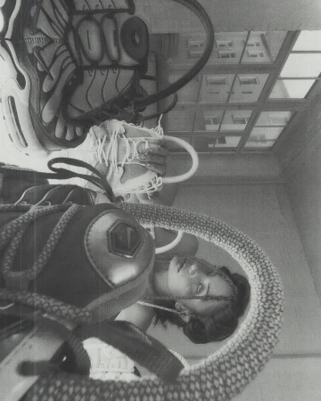 Monochrome studio shot of a woman with a soccer ball, sneakers, and athletic gear, creating an upside-down, surreal composition with natural light.