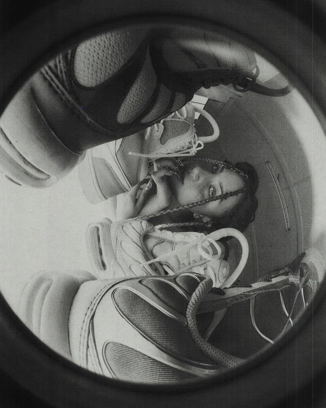 Monochrome portrait of an adult female framed by athletic shoes within a circular border, creating a unique and surreal composition.
