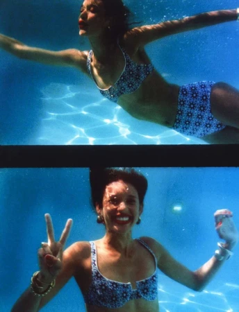 Underwater two-frame diptych of a smiling woman in a patterned blue bikini flashing a peace sign in a pool by Hans Neumann.