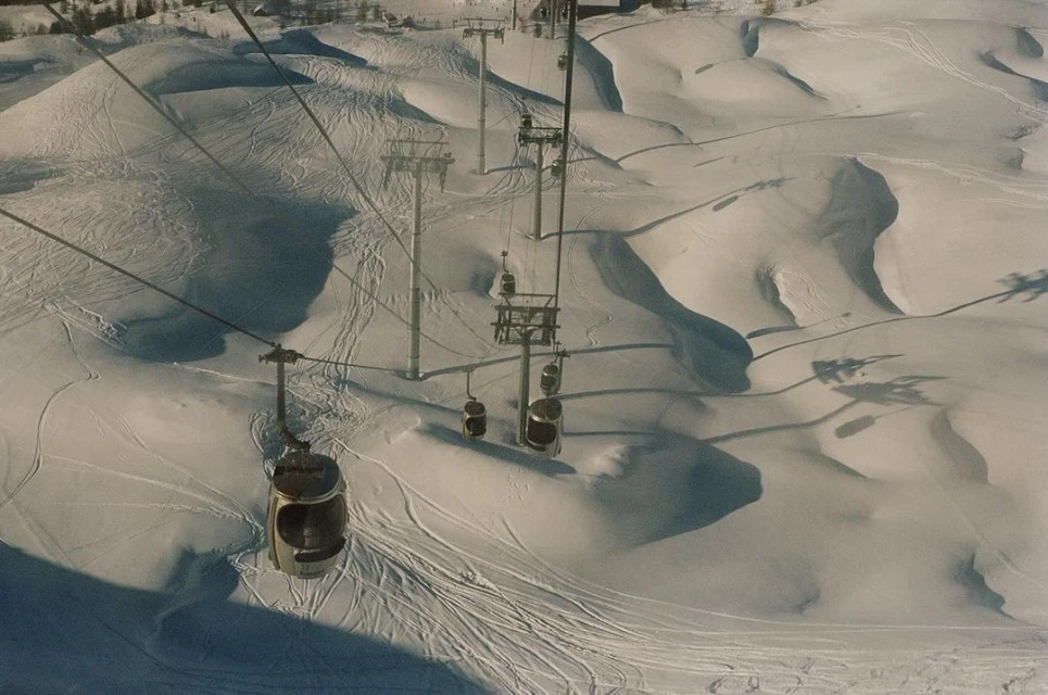 High-angle view of a ski resort with gondola lift cars and snow-covered hills, creating a scenic winter landscape.