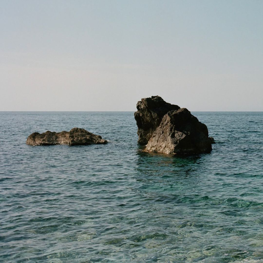 Two large rocks are surrounded by water in this outdoor landscape. The scene is captured in natural light on a clear day.