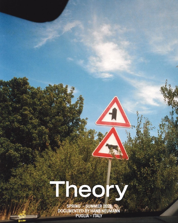 Traffic sign with cow symbol in a rural area under a blue sky, seen from inside a car, with trees and greenery in the background.