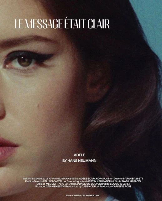 Close-up portrait of a woman with dramatic eye makeup. The image features text overlay in white, with a soft, diffused blue background.