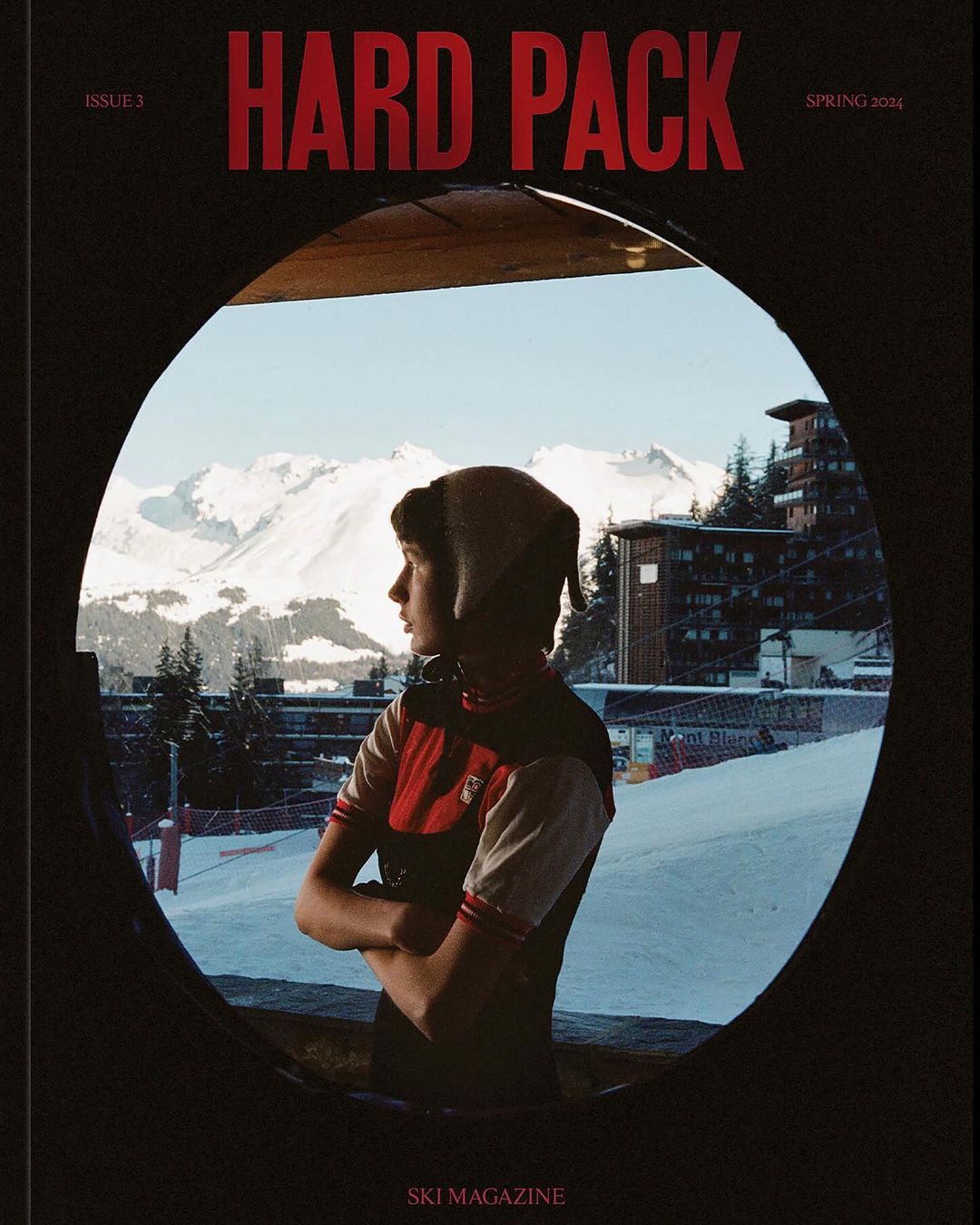 Magazine cover featuring a person looking out from an opening onto a snowy mountain landscape. Winter sports and editorial photography.