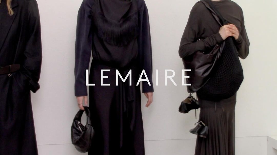 Three fashion models showcase black outfits and stylish handbags against a neutral backdrop, emphasizing minimalist style and luxury accessories.