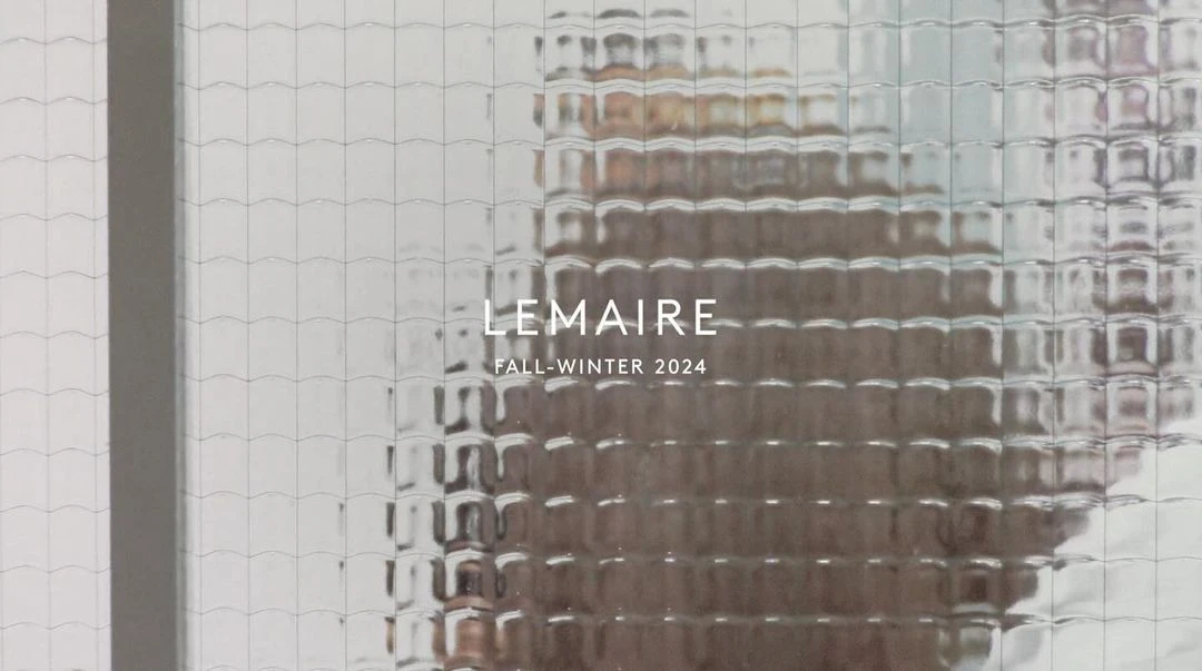Text overlay on textured glass, featuring brand name and season. Image provides a glimpse through an obscured window.