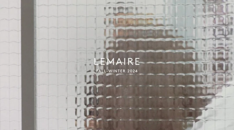 Text overlay on textured glass, featuring brand name and season. Image provides a glimpse through an obscured window.
