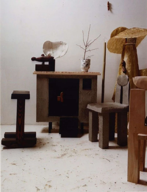Arrangement of handmade wooden chairs and furniture pieces in a photo studio setting against a neutral background.