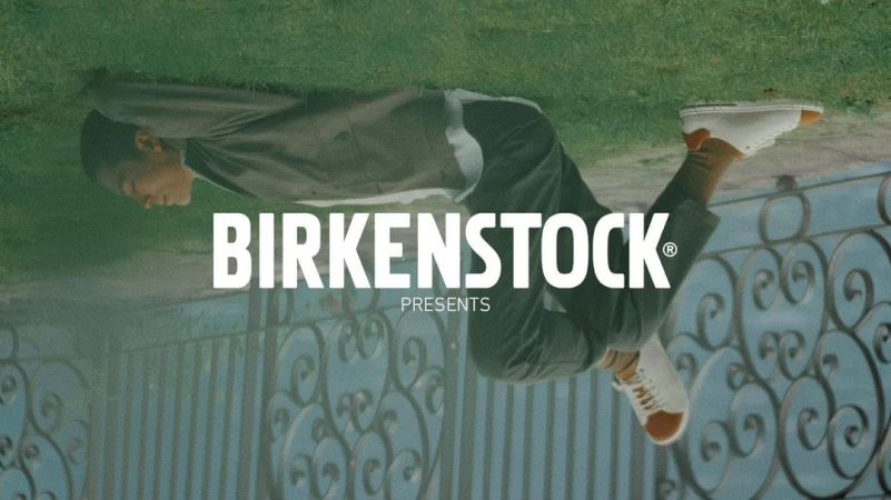 An upside-down shot features a person in casual clothing, tan socks, and white Birkenstock sneakers, next to the Birkenstock logo.