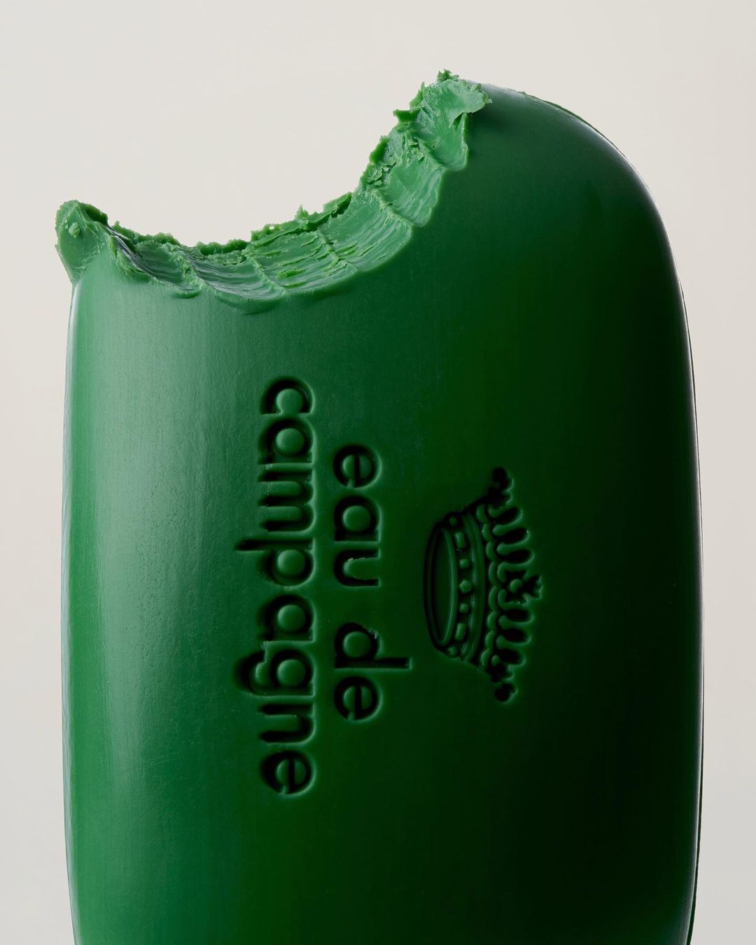 Close-up of a bitten, green-colored bar of 'Eau de Champagne', highlighting texture and color against a neutral background.