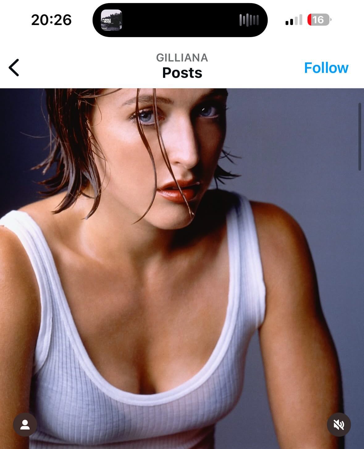Portrait of a Caucasian adult female with wet brown hair and blue eyes wearing a white tank top against a grey background.