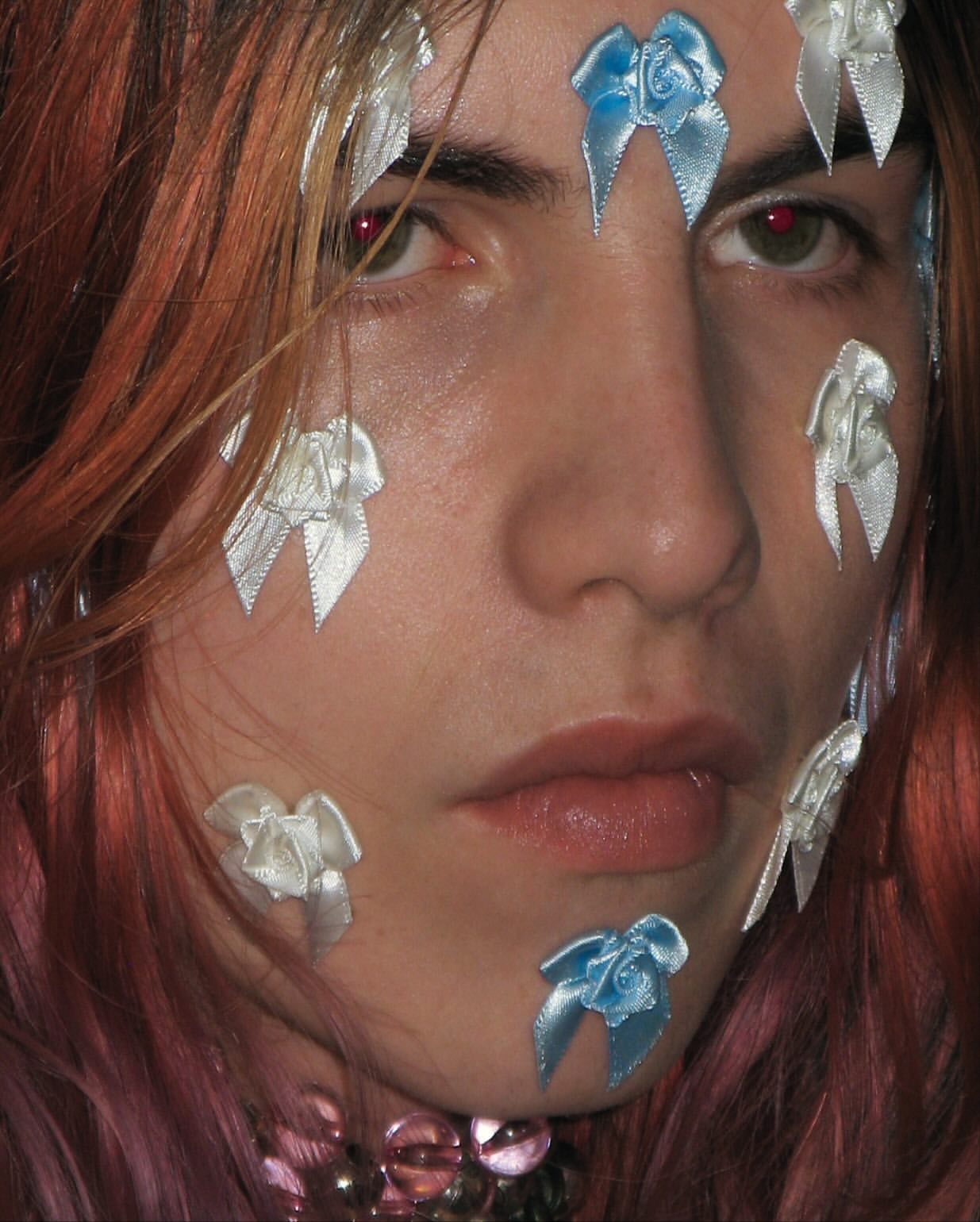 Close-up portrait of a person with ribbons on their face and long hair, focusing on unique aesthetic and visual details of the headshot.