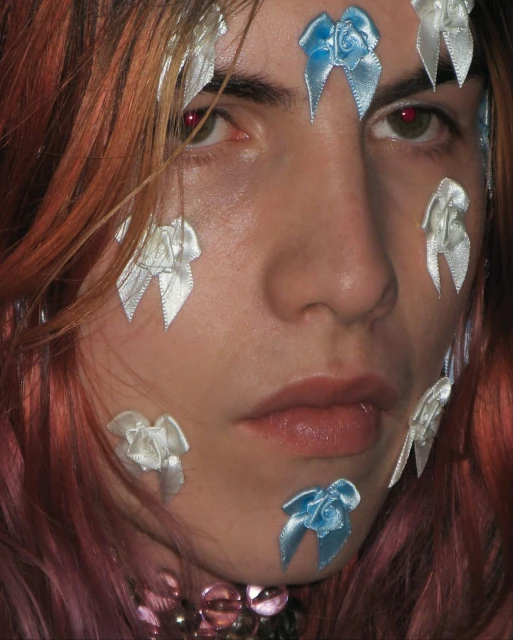 Close-up portrait of a person with ribbons on their face and long hair, focusing on unique aesthetic and visual details of the headshot.