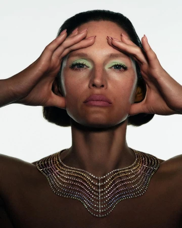 Close-up portrait of a woman wearing a jewelled statement collar and pastel green eyeshadow photographed by Harley Weir