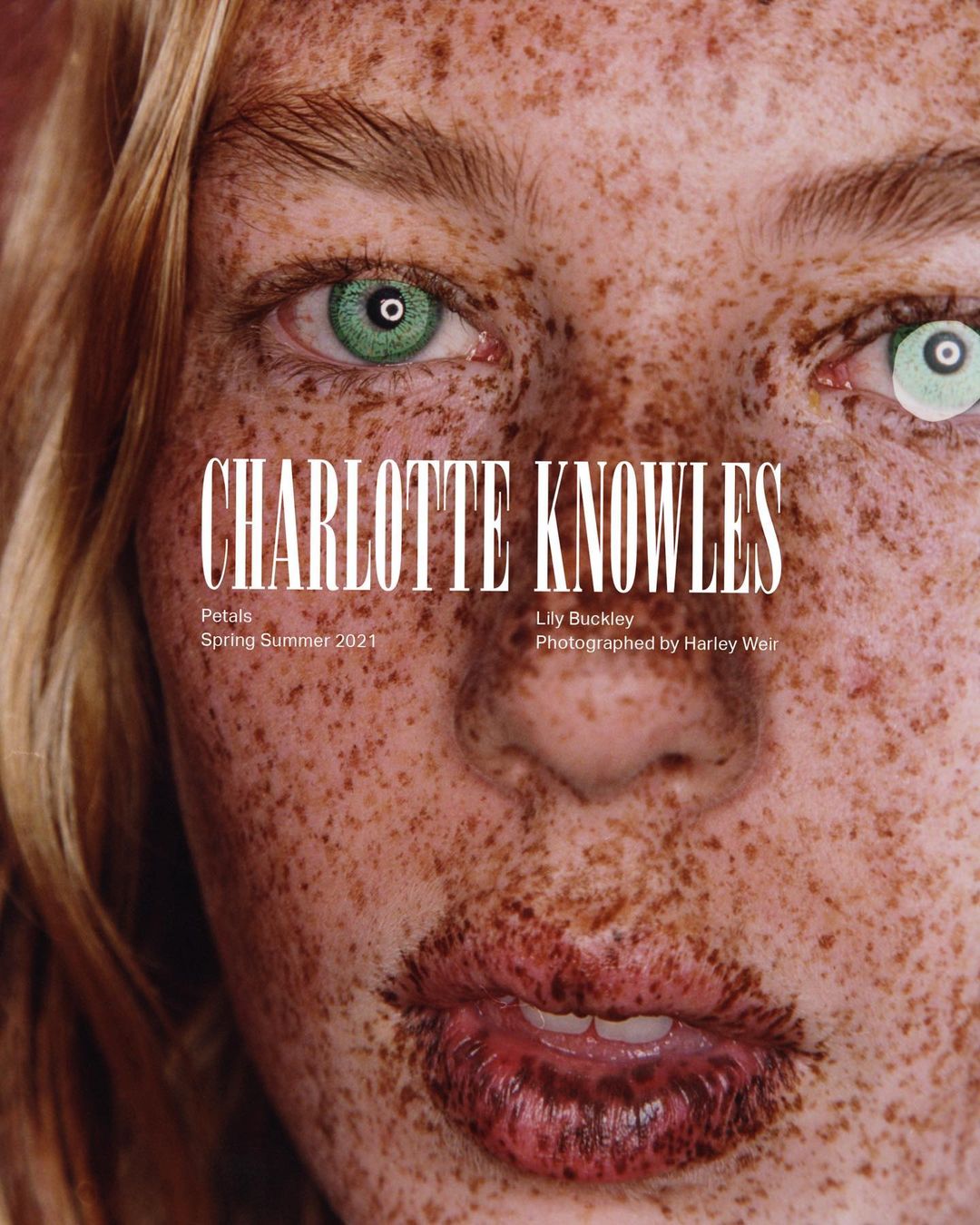 Close-up portrait of a freckled woman with heterochromia eyes, fair hair, and full lips, featuring a fashion magazine cover design with bold typography.