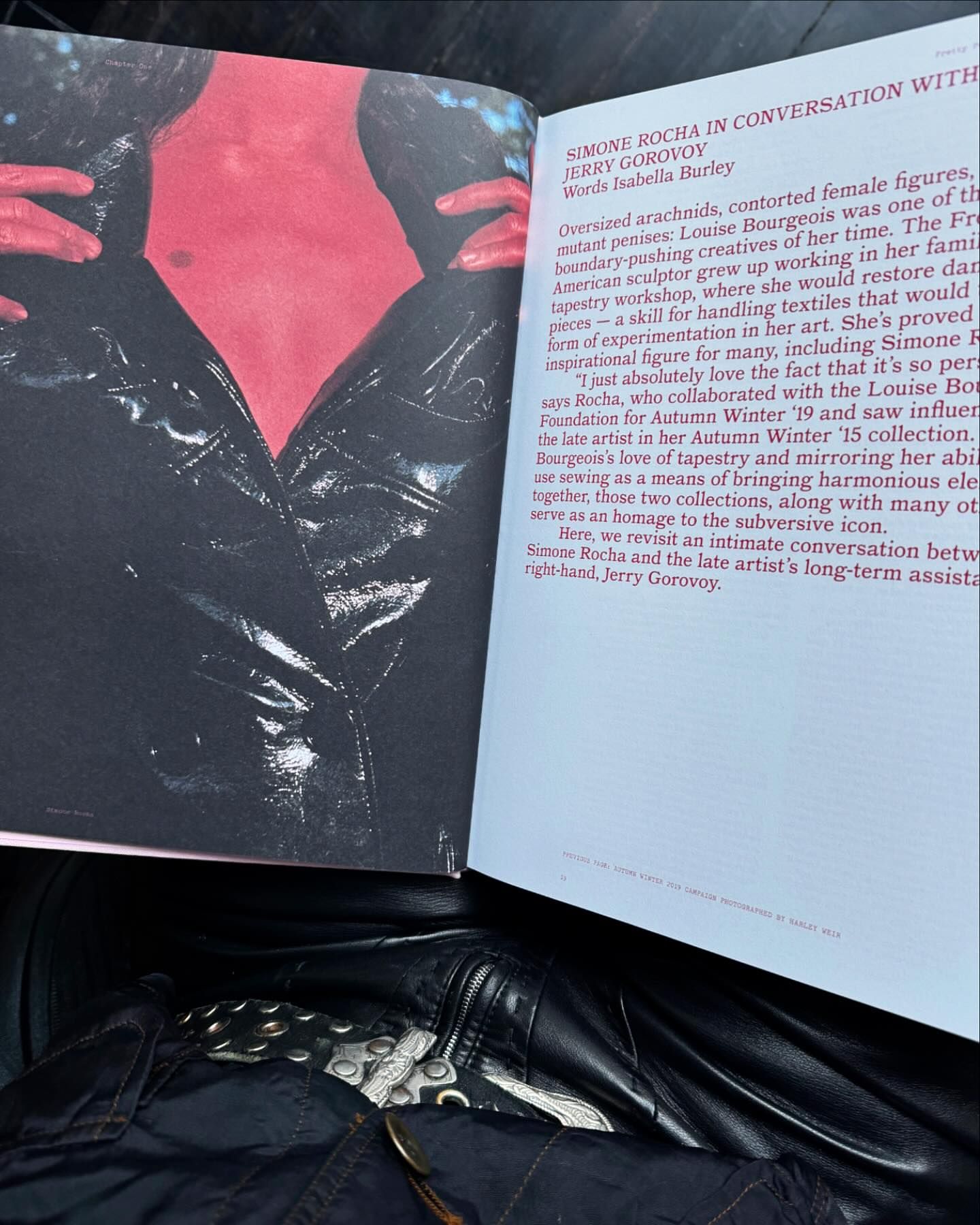Open magazine page with a torso in a vinyl jacket and conversation text featuring Simone Rocha and Jerry Gorovoy on pale pink paper.