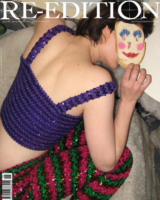 Young woman in a blue top and patterned pants poses with a cookie over her face, set against a neutral background. Magazine cover.