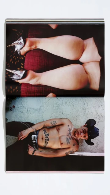 Open book with photograph featuring person lying down, tattoo on torso, and person wearing heels with legs and backside raised up.