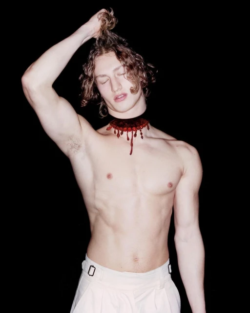 Conceptual portrait of a shirtless male with long wavy hair and a detached head effect against a dark backdrop in a studio setting.