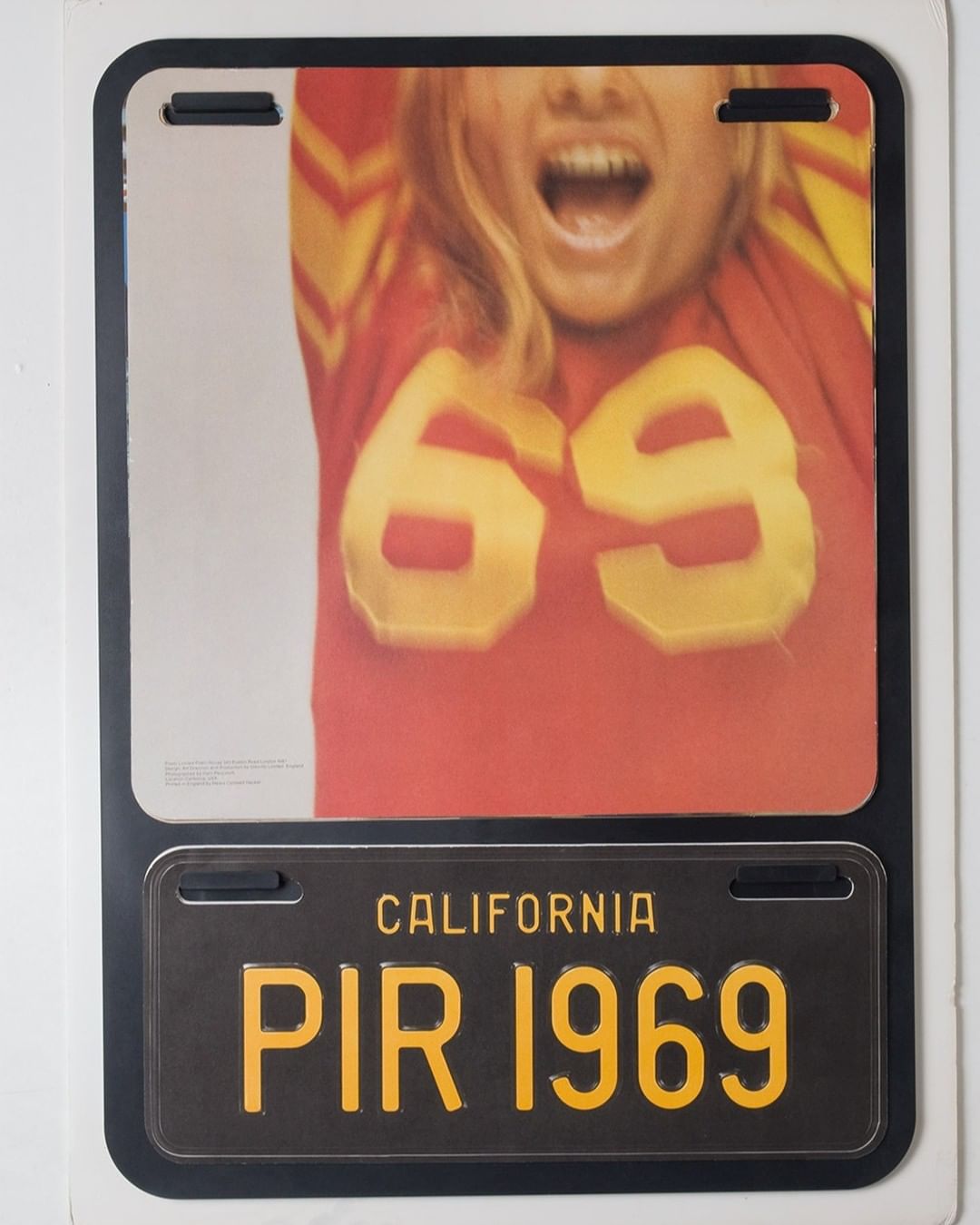 License plate display featuring a blonde-haired woman with the number '69' on her shirt and 'PIR 1969' on a California license plate.