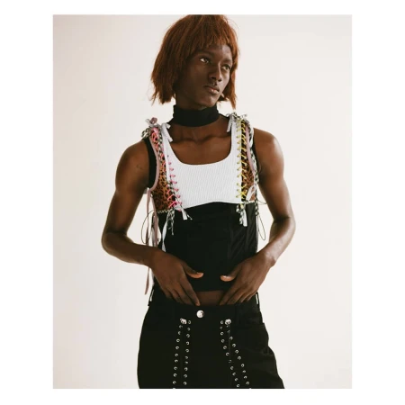 Model wearing a layered white and black top with lace-up details and a black choker against a neutral background