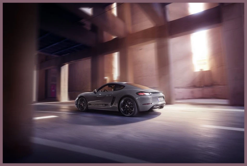 Grey Porsche coupe driving through a concrete structure, showcasing modern automotive design in an urban-industrial environment with soft lighting.