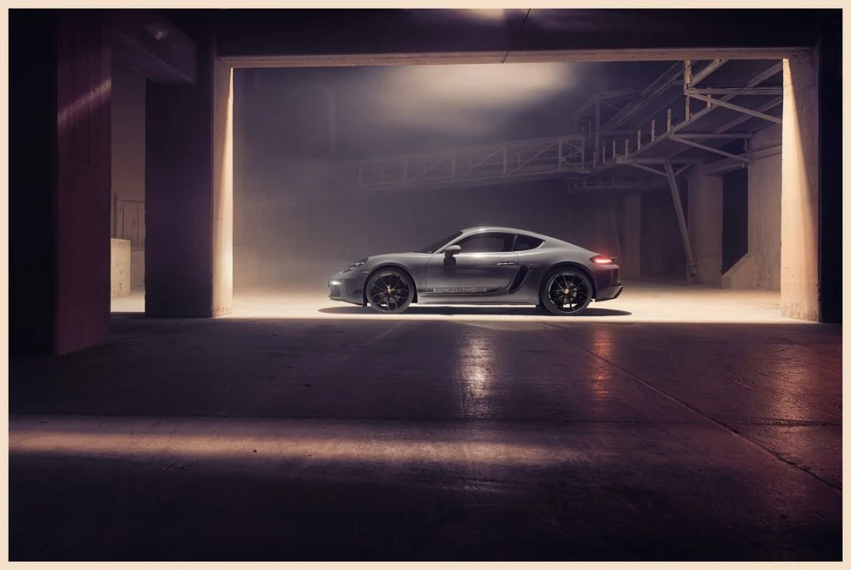 Silver Porsche coupe parked in a garage with soft lighting. Automotive photography showcasing the car's sleek design in a minimalist setting.