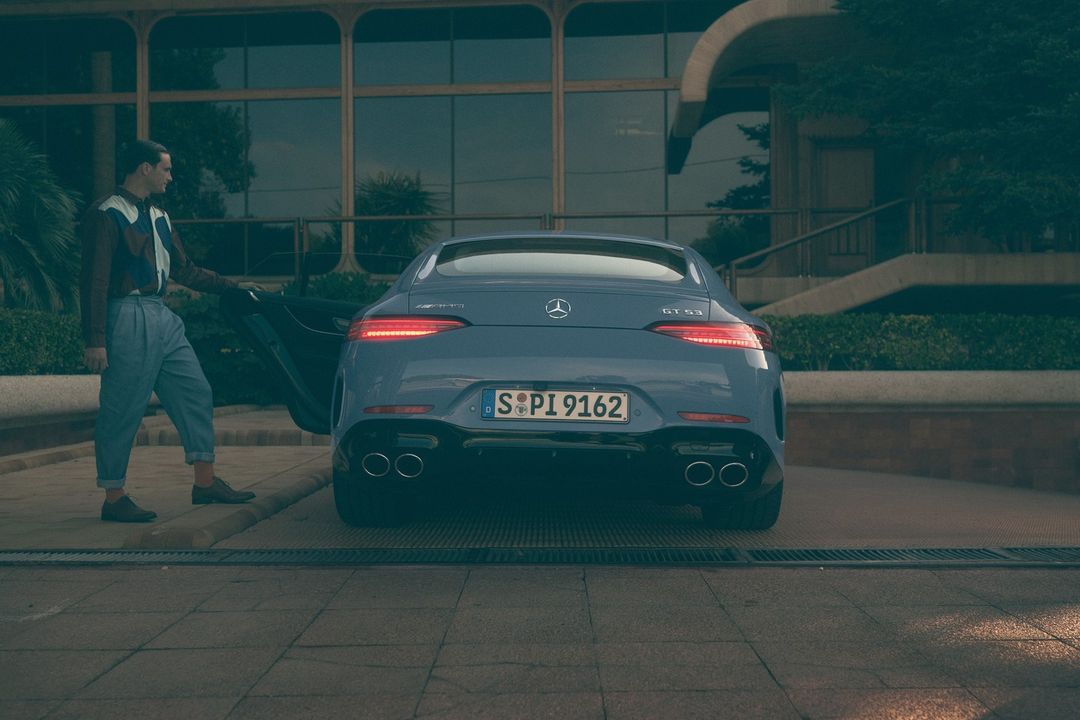 A blue Mercedes-Benz AMG GT 63 stands outdoors with a man opening the driver's side door, under natural lighting.