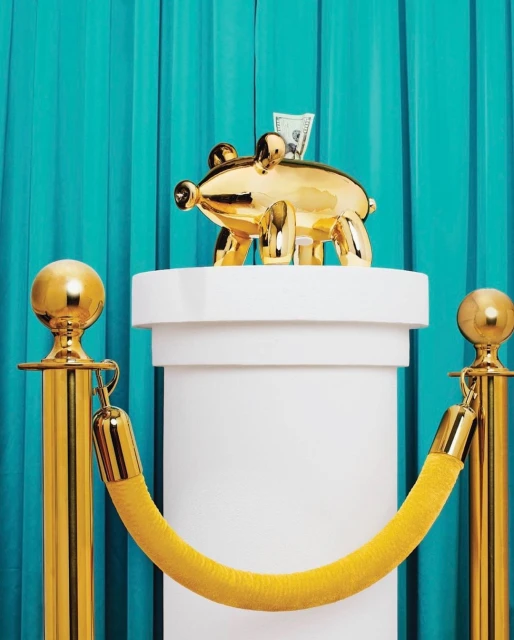 Close-up of a golden piggy bank on a white column, guarded by gold stanchions with yellow rope, set against a vibrant turquoise curtain backdrop.