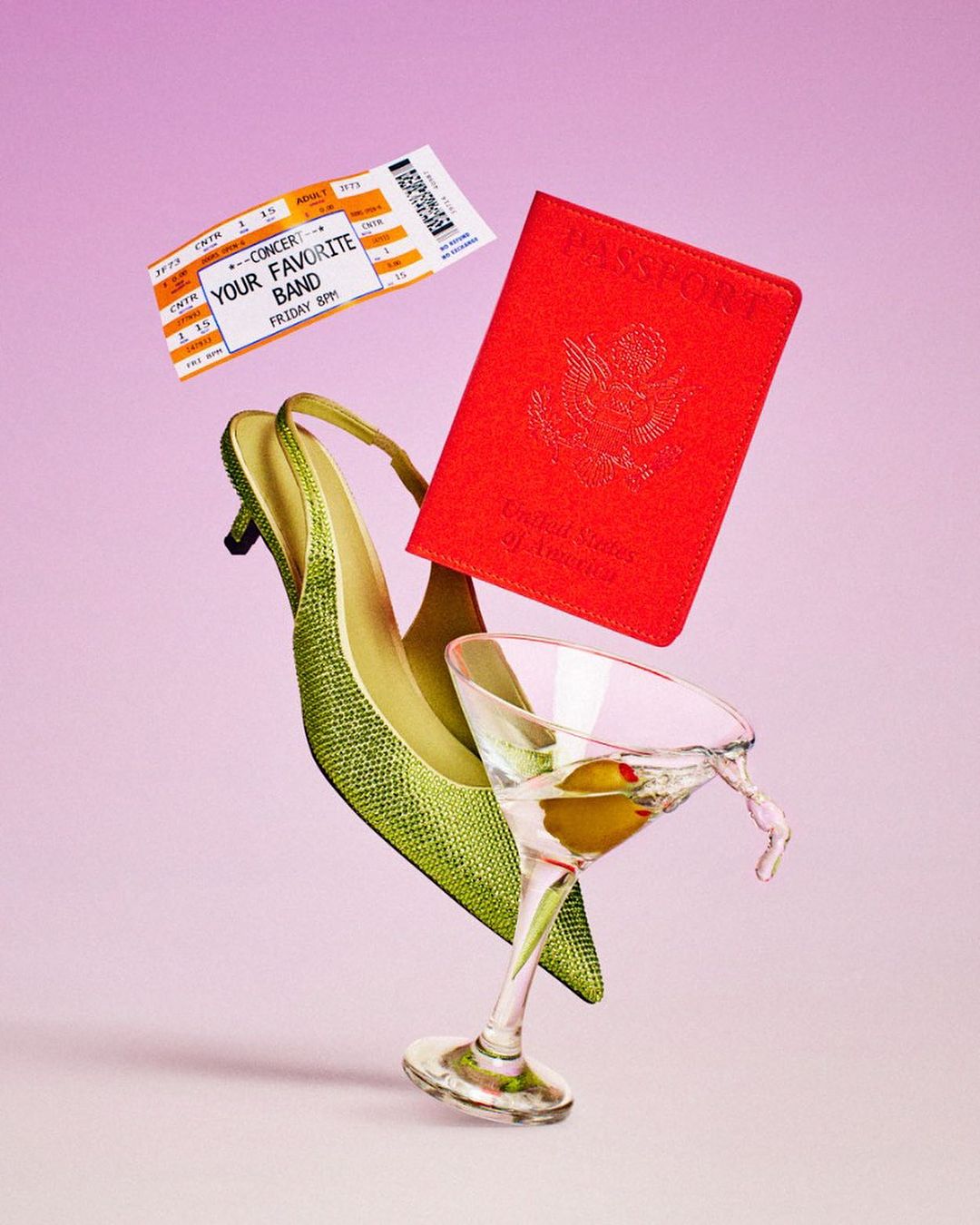 Still life of an open US passport, green high-heeled shoe, martini glass, and concert ticket floating in front of a pink background.