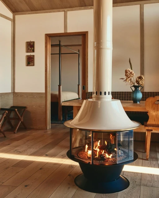 Indoor shot of a modern living room featuring a unique fireplace, wooden furniture, and view of a bedroom through an open doorway.