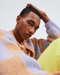 Close-up portrait of a Black man with face gems wearing a checkered cardigan by photographer Heather Moore
