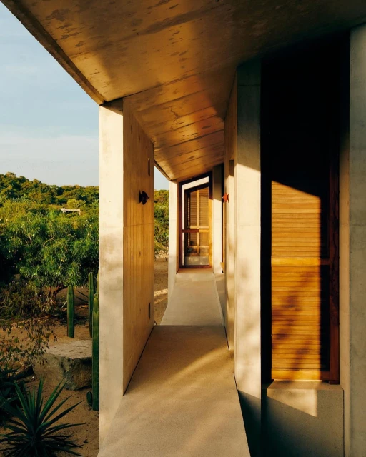Exterior view of a modern concrete building with wooden accents, showcasing minimalist architecture and integration with the natural landscape.