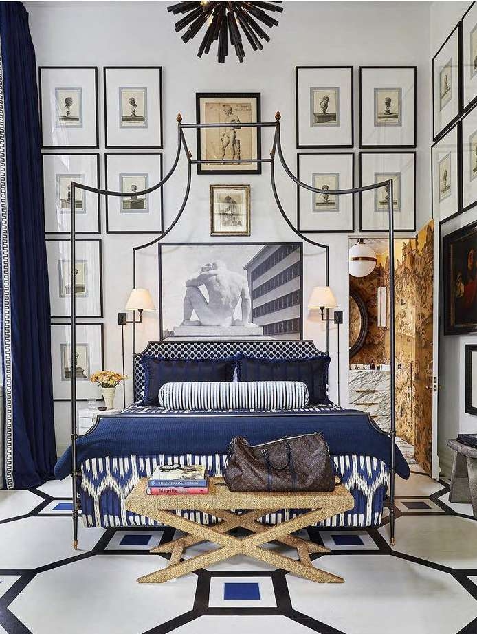Ornate bedroom interior with four-poster bed, graphic floor, textile details, framed artwork, and neutral color palette.