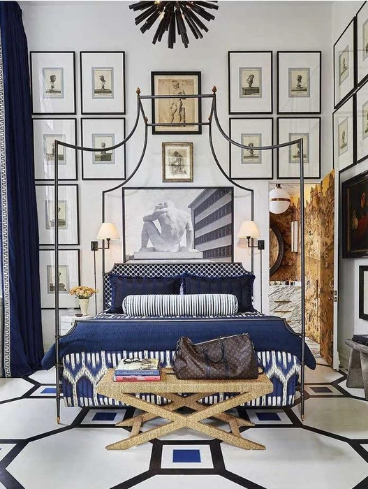 Luxurious bedroom interior with a wrought iron canopy bed, blue patterned linens, and walls decorated with framed prints.
