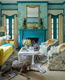 A brown dog rests on a zebra rug in a vibrant turquoise living room with yellow sofa, patterned armchairs, and a fireplace.