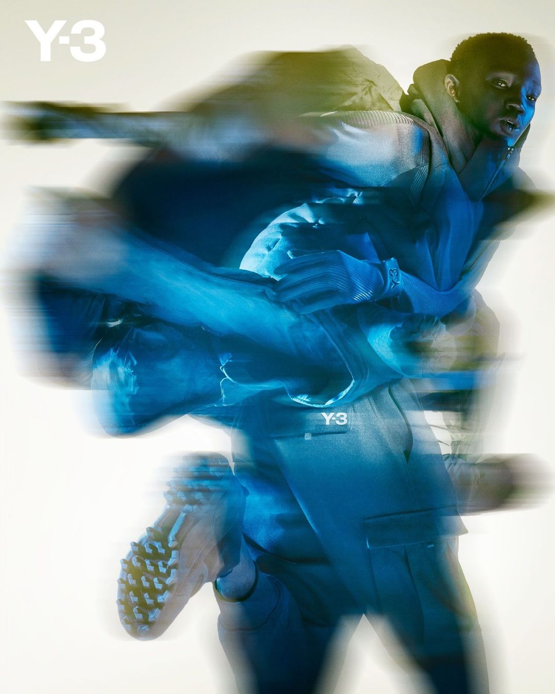 Fashion shot of a Black male model in motion wearing apparel with a Y-3 logo. The image features long exposure blurring effects.
