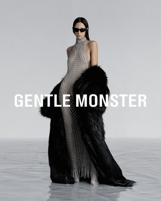 Fashion shot: A woman in a silver gown and black fur coat poses in a studio with 'GENTLE MONSTER' text overlay.