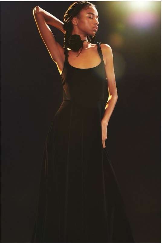 Black woman in a long black dress posing under dramatic lighting by photographer Heji Shin in London.