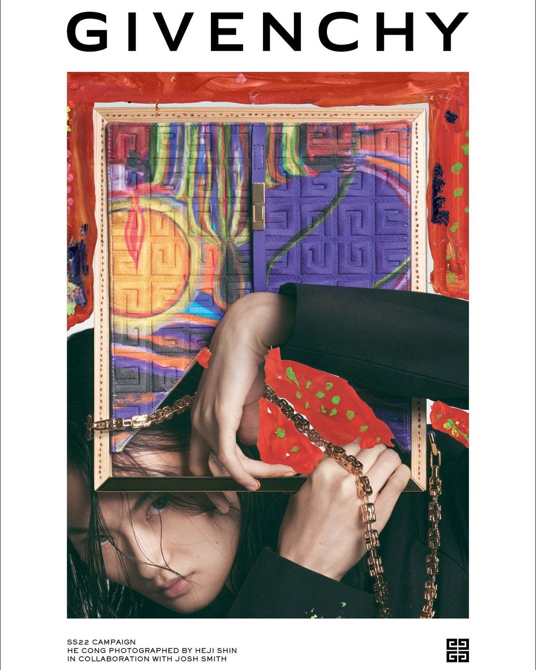 Fashion editorial featuring an Asian model in a black suit holding a picture frame with gold chain, set against colorful abstract artwork.