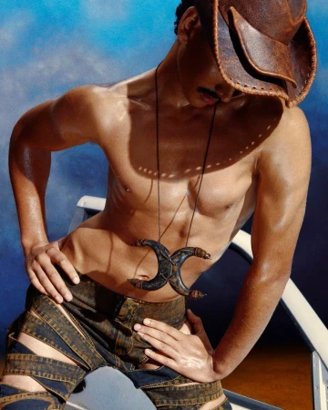 Shirtless man wearing a brown leather cowboy hat and strappy patterned pants photographed by Heji Shin.
