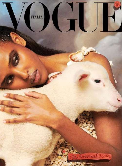 Vogue Italia cover featuring a Black female model embracing a white lamb, against a painted backdrop, evoking classic art.