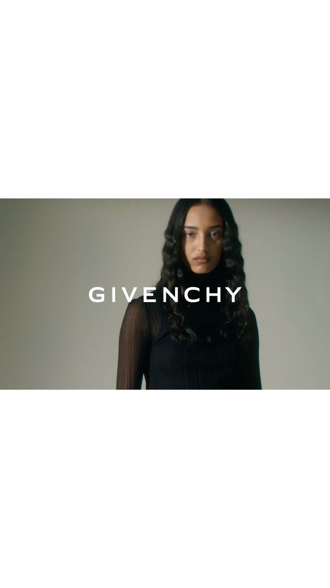Model in black turtleneck standing against a neutral studio background with bold Givenchy text overlaid across the center.