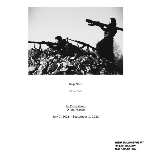 Black and white art photograph of two figures atop a stone structure holding weapons, against a clear sky.