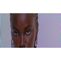 Extreme close-up portrait of a Black woman with braided hair and hoop earrings, displayed on a pixelated screen.