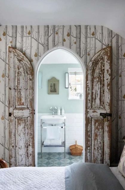 Bathroom with antique white doors, white washbasin, subway tile, and nature-themed wallpaper in an indoor setting.