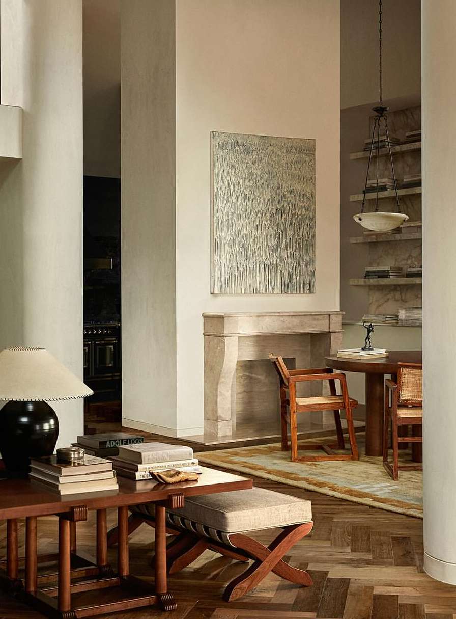 Interior design in a warm, neutral color palette features a fireplace, abstract art, and modern furniture with wood and fabric textures.