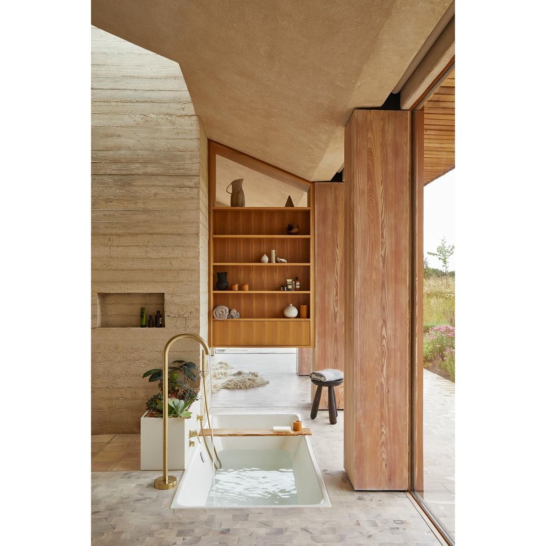 Modern bathroom interior featuring a freestanding bathtub, natural light, and wood and stone elements creating a spa-like ambiance.
