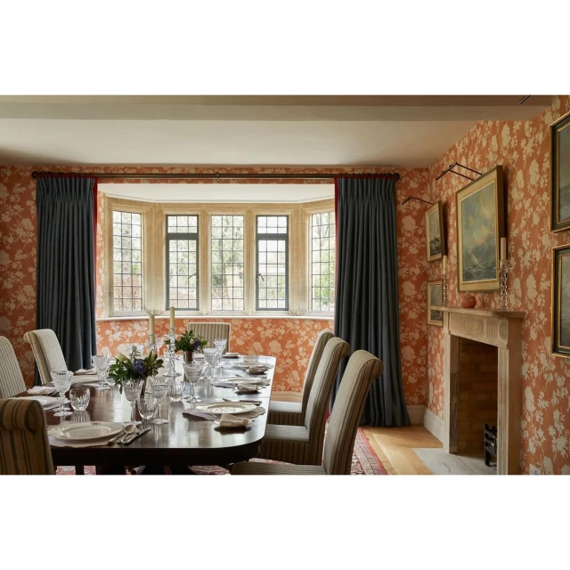 Formal dining room featuring a dark wood table set with plates and glassware, surrounded by upholstered chairs and floral wallpaper.
